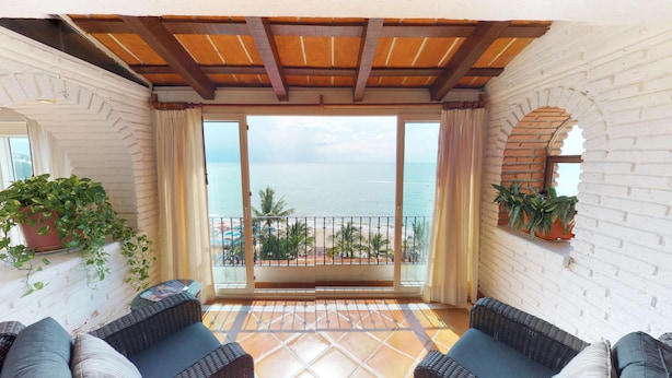 A balcony with wicker furniture, a potted plant, and a view of the sea. - Great Penthouse at El Dorado 3BD Penthouse for rent in Los Muertos Beach, Puerto (Puerto Vallarta)