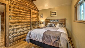 Ein Schlafzimmer mit einer Holzwand, einem Bett mit Kopfteil und einem Fenster.