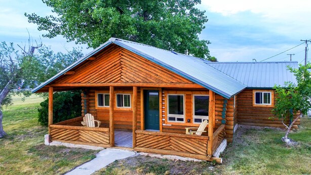 Eine Blockhütte mit Veranda, zwei Fenstern und einer Tür.