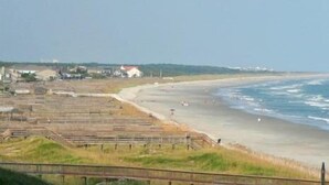 A coastal area with a beach, a few buildings, and a clear sky. - Retreat 514 - 2nd Row, Great View, Pool, Ocean! (Pawleys Island)