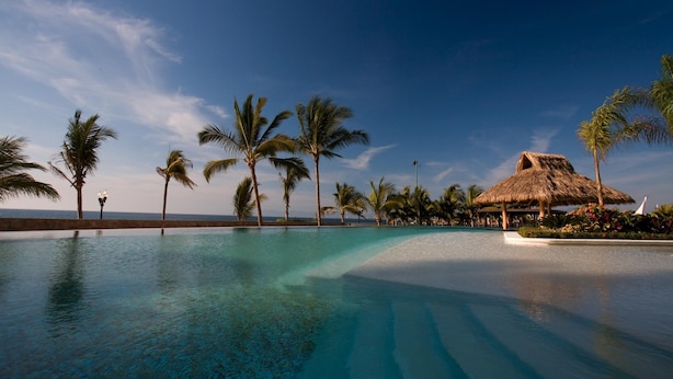 A clear blue pool with a thatched-roof structure, surrounded by palm trees and a clear sky. - Luxury Beachfront Condo! 3BD Condo for rent in Los Muertos Beach, Puerto vallart (Puerto Vallarta)