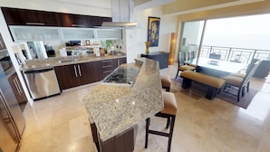 A modern kitchen with granite countertops, stainless steel appliances, and a dining area with a large table and chairs. - Luxury Beachfront Condo! 3BD Condo for rent in Los Muertos Beach, Puerto vallart (Puerto Vallarta)