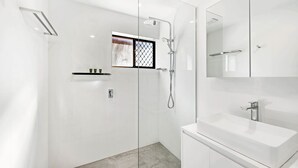 A modern bathroom with a glass-enclosed shower, a white sink, and a mirror above the sink. - Anjuna, 2 bedroom apartment on canal (Mooloolaba)