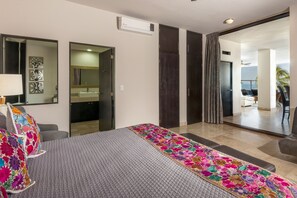 Une chambre d’hôtel moderne avec un grand lit, une salle de bain dotée d’un miroir et d’un lavabo, et un balcon avec vue.