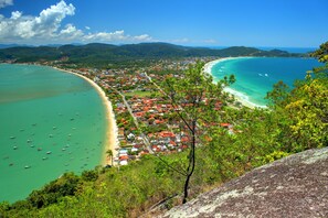 A coastal town with a beach, boats, and lush greenery.