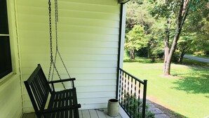 A porch with a wooden swing and a stone planter.