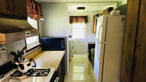 A compact kitchen with a stove, microwave, and refrigerator.