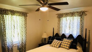 A bedroom with a bed, a nightstand, a lamp, and a ceiling fan.