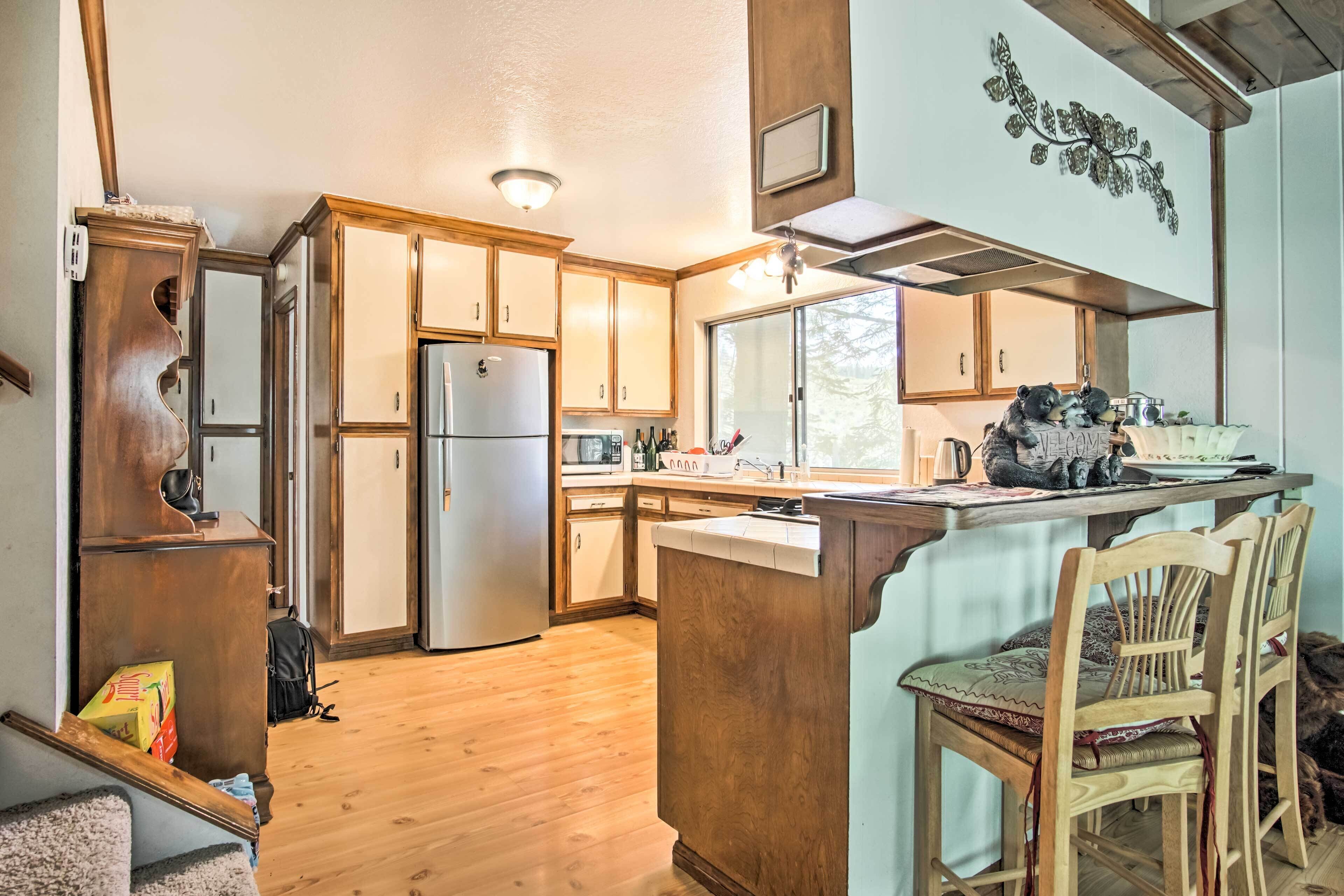 A kitchen with wooden cabinets, a refrigerator, a dining area with a table and chairs, and a window providing natural light.