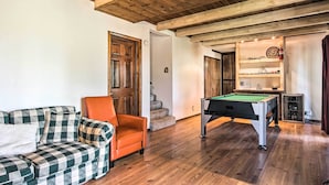 Une pièce chaleureuse avec une table de billard, un canapé et un plafond en bois.