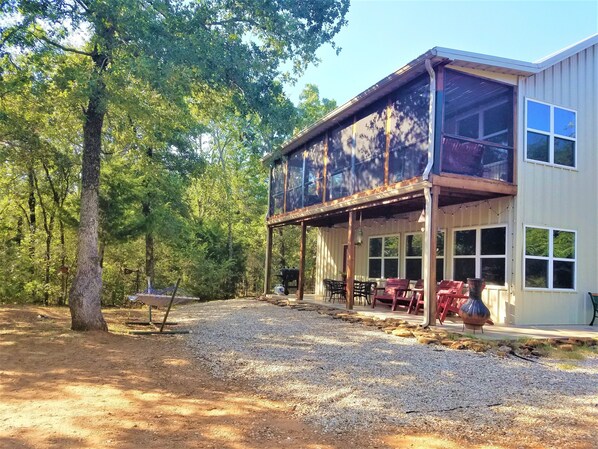 A rustic two-story building with a covered patio area, surrounded by trees. -  A Beautiful Escape from the City. Explore Nature and Enjoy the Lake! (Hillsboro)