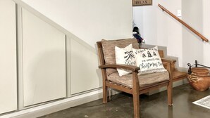 Una escalera con barandilla de madera, una silla con cojín y un letrero en la pared.