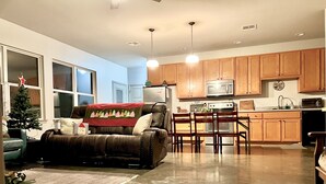 Una cocina moderna con armarios de madera, un comedor con mesa y sillas, un sofá de cuero y un árbol de Navidad.