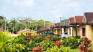 A row of colorful, single-story buildings with a car parked in front. - 2Bedrooms 2Bathroom - Swimming pool - Gated community - Drier - Free Wifi (Ocho Rios)