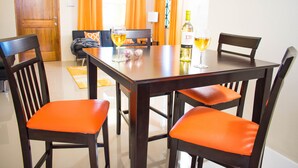 A dining area with a wooden table, four orange chairs, a bench, and a bottle of wine. - 2Bedrooms 2Bathroom - Swimming pool - Gated community - Drier - Free Wifi (Ocho Rios)