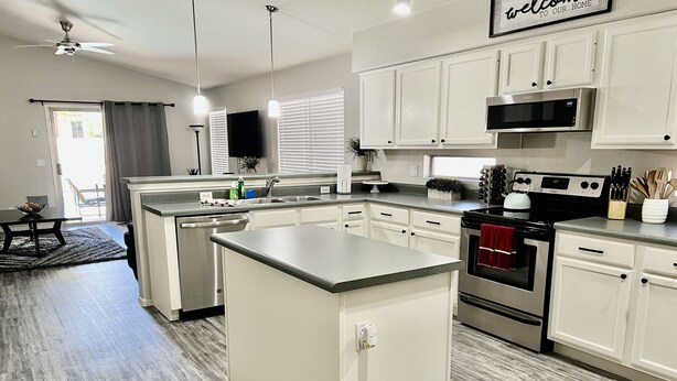A modern kitchen with white cabinets, stainless steel appliances, and a central island.