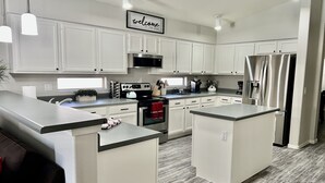 A modern kitchen with white cabinets, stainless steel appliances, and a central island.