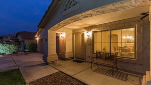 A residential building with a well-lit entrance, a bench outside, and a visible door.