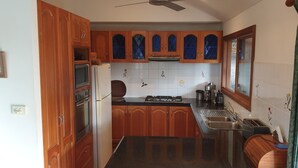 Une cuisine avec des meubles de rangement en bois, une cuisinière, un évier et une fenêtre donnant sur un beau paysage.