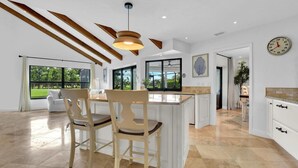 A spacious kitchen with a central island, large windows, and a view of the outdoors. - TORREY PINES - Single Family Pool Home in Lely Country Club (Naples)