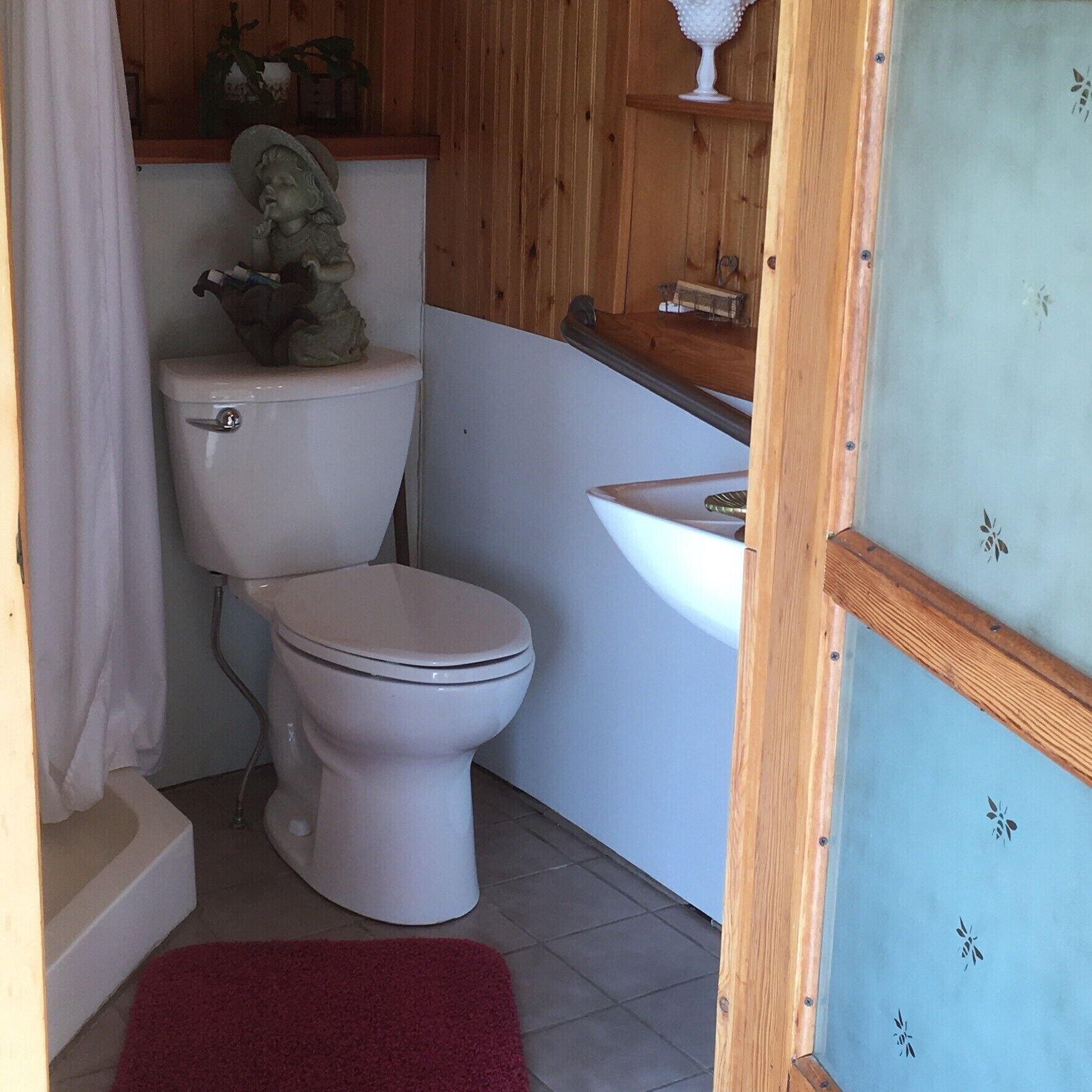 Een kleine badkamer met toilet, wastafel en douchehoek.