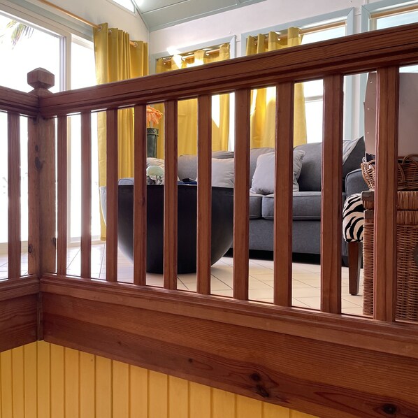 Barandilla de madera de una escalera con vista a un salón.