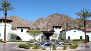 A building with a fountain, palm trees, and mountains in the background. - Mountain Views! Mountains, Palm Trees and Blue Skies - Upstairs with Garage, Pet Friendly (L56) (La Quinta)