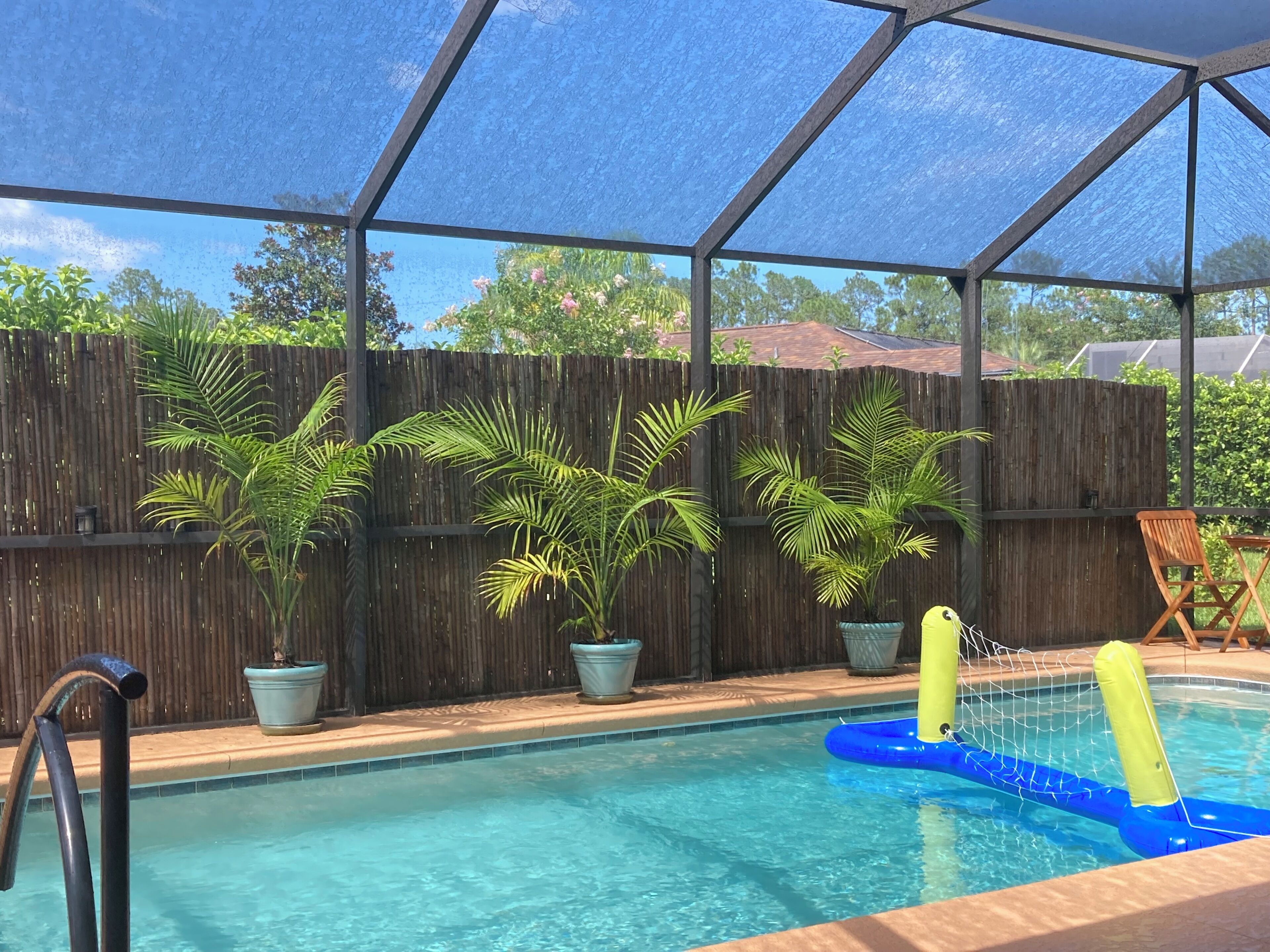 A pool area with a wooden fence, potted plants, and a blue inflatable pool with a yellow float.