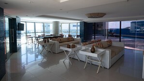 A spacious living area with a large sofa set, a dining table, and a view of the ocean. - A retreat with a perfect sea view, 2 bedrooms, Wi-Fi, 24-hour concierge, rotating garage. (Natal)
