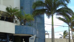 A building with a blue-tiled facade, a sign reading "Cristalla Residential 95", and a palm tree in the foreground. - A retreat with a perfect sea view, 2 bedrooms, Wi-Fi, 24-hour concierge, rotating garage. (Natal)