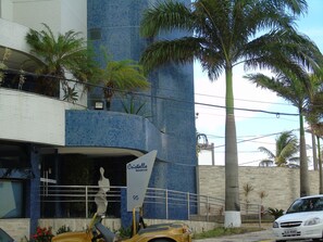 Ein Gebäude mit einer blau-gefliesten Fassade, einem Schild mit der Aufschrift 'Cristalla Residential 95' und einer Palme im Vordergrund.