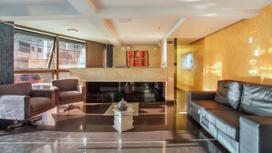 A modern lobby with a fireplace, leather sofas, and a glass coffee table. - A retreat with a perfect sea view, 2 bedrooms, Wi-Fi, 24-hour concierge, rotating garage. (Natal)