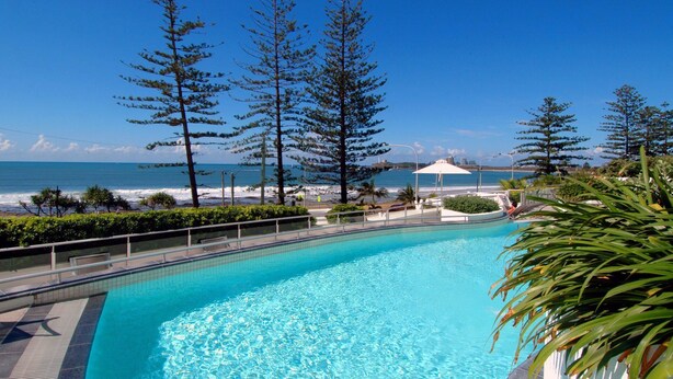 Una piscina con vista sull'oceano e alberi alti.