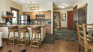 A kitchen with wooden bar stools, a stainless steel refrigerator, and a tiled backsplash. - Entire 1BR apt, Sleeps 4, Wi-Fi, Close to Slopes (Vail)