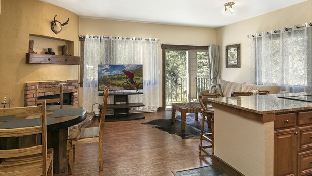 A spacious living area with a fireplace, wooden furniture, and a large window with curtains. - Entire 1BR apt, Sleeps 4, Wi-Fi, Close to Slopes (Vail)