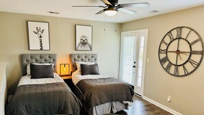 Une chambre avec deux lits, une grande horloge murale et un ventilateur de plafond.