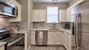 Une cuisine moderne avec des meubles blancs, un réfrigérateur en acier inoxydable, un lave-vaisselle et un four encastré.