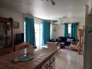 Ett mysigt vardagsrum med ett klinkergolv, en tv, en soffa och en matplats med ett bord och stolar.