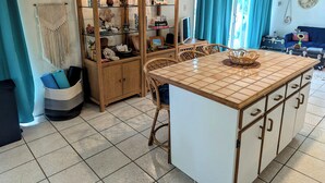 Een keuken met een centraal eiland, houten kastjes en een glazen vitrine.