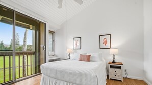 Un dormitorio con una cama grande, una mesita de noche con lámpara y un ventanal corredero que da a un balcón.