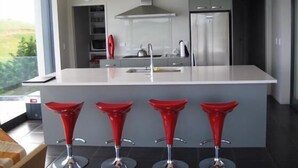 A modern kitchen with a central island, stainless steel appliances, and four red bar stools.
