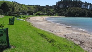 A coastal landscape with a grassy area and a sandy beach.
