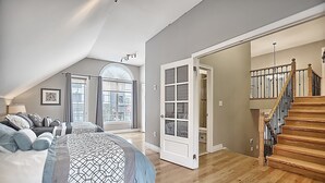 Quarto com uma cama grande, um armário e uma escada.