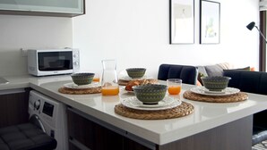 A modern kitchen with a microwave, coffee maker, and a breakfast setup including bowls and orange juice. - Phaedrus Living: Seaside Luxury Flat Lighthouse 53 (Paphos)