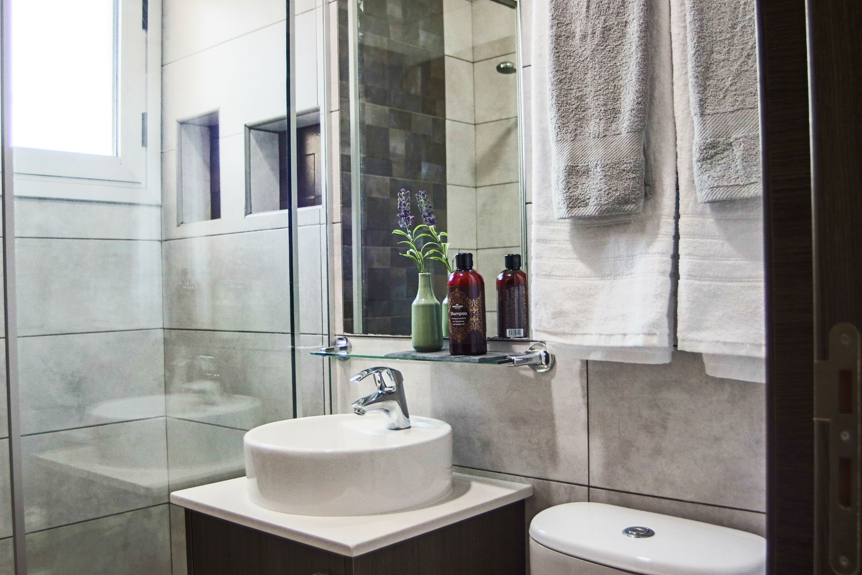 A bathroom with a glass shower enclosure, a white sink, and a toilet.