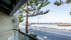 Een balkon met uitzicht op een jachthaven en een weg.