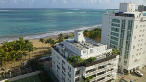Un hotel con terraza en la azotea, vistas a la playa y zona de estacionamiento.