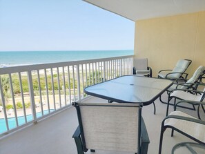 A balcony with a glass table and chairs, overlooking a beach and ocean. - Cambridge 302 Beautiful Views from Large Oceanfront Balcony (Pawleys Island)