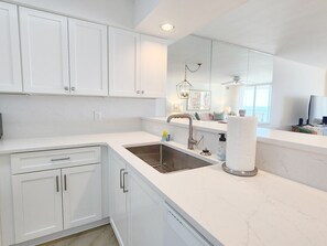 A modern kitchen with white cabinetry, a stainless steel sink, and a countertop.