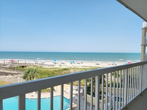 A balcony with a view of a beach, a pool, and a lifeguard tower. - Cambridge 302 Beautiful Views from Large Oceanfront Balcony (Pawleys Island)